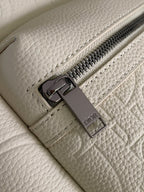 Cream backpack with metal zipper pull and Dior logo tag on interior pocket.