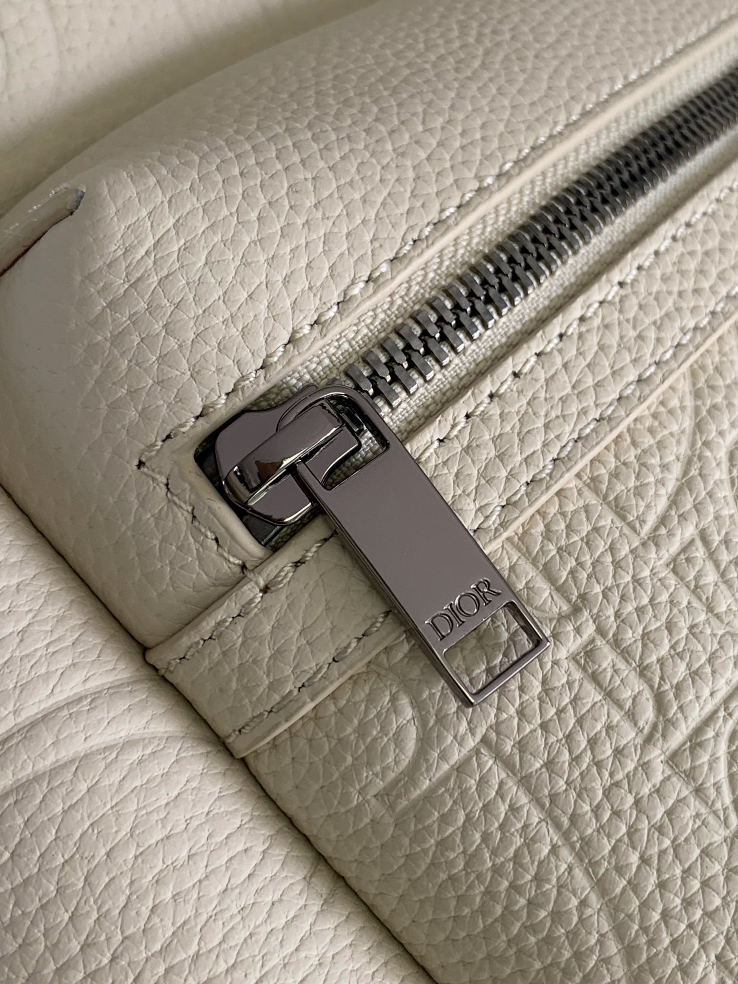 Cream backpack with metal zipper pull and Dior logo tag on interior pocket.
