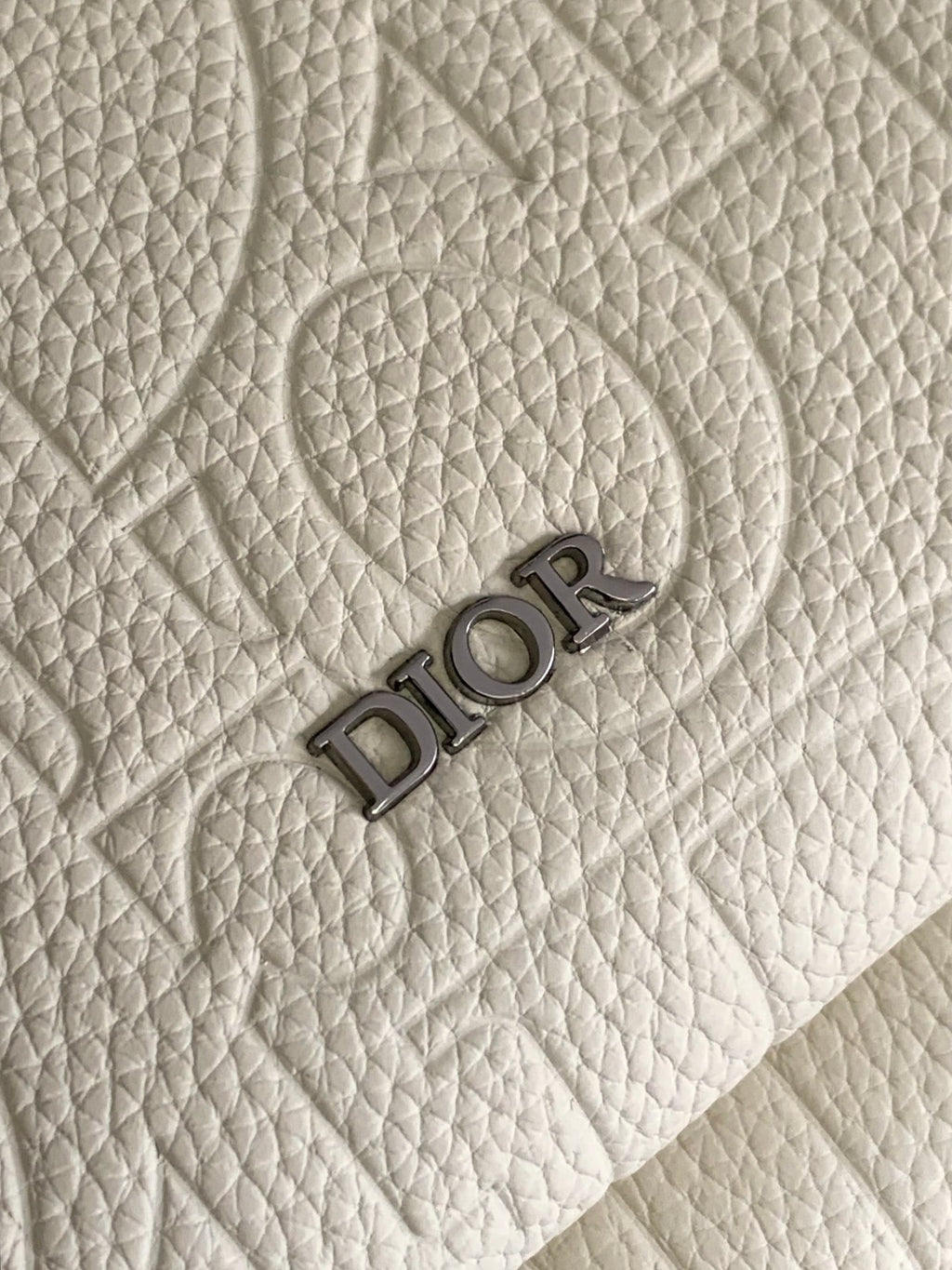 Cream textured fabric with embossed Dior logo lettering.