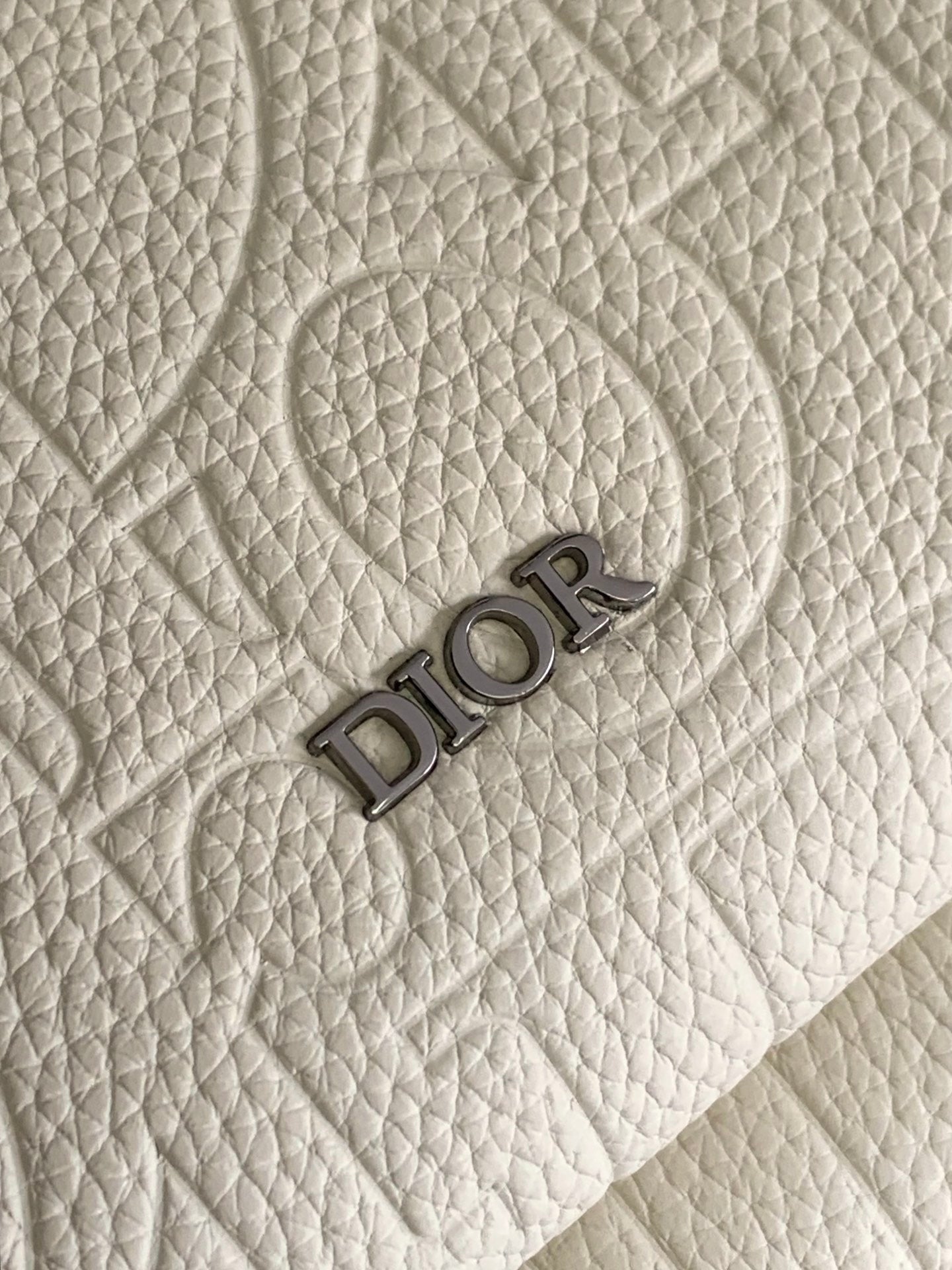 Cream textured fabric with embossed Dior logo lettering.