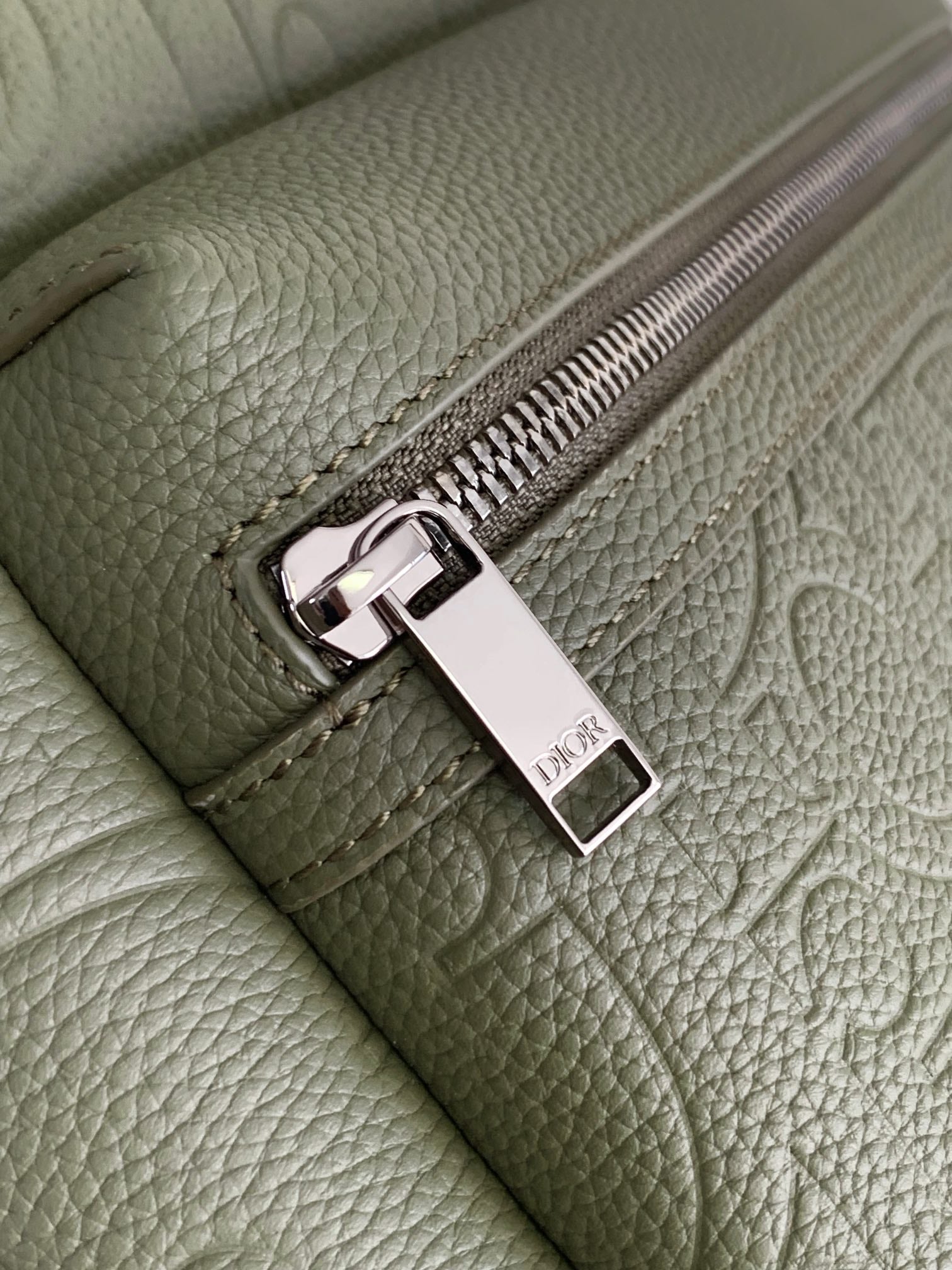 Olive Dior mini bag detail: silver zipper pull with rectangular logo tag