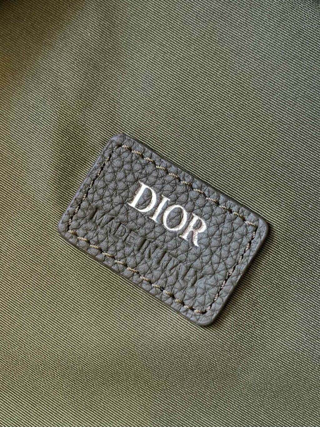 Olive-green Dior fabric brand patch with stitched border and logo