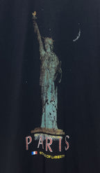 Close-up of dark T-shirt front showing “PARIS” text under the Statue of Liberty print