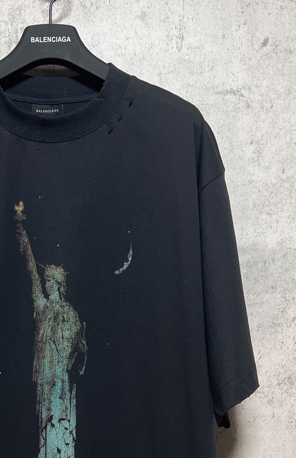 Dark T-shirt with partial Statue of Liberty graphic and speckled print on the front
