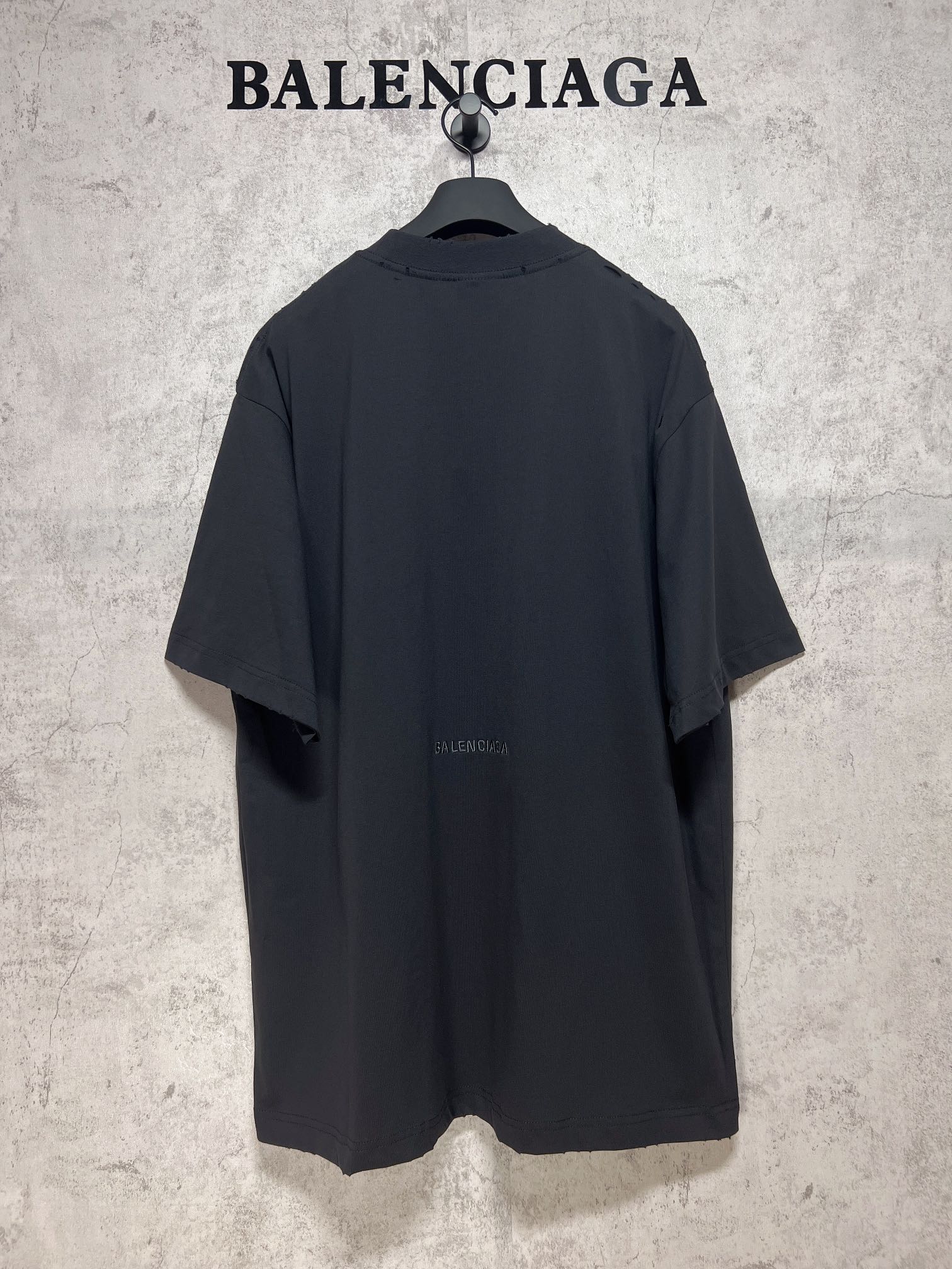 Dark back view T-shirt on a hanger with small Balenciaga logo near the center