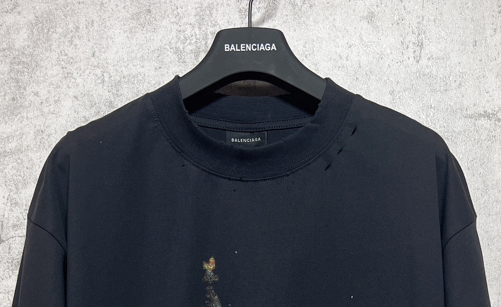 Dark crewneck T-shirt with Balenciaga logo at the collar; small front print flecks