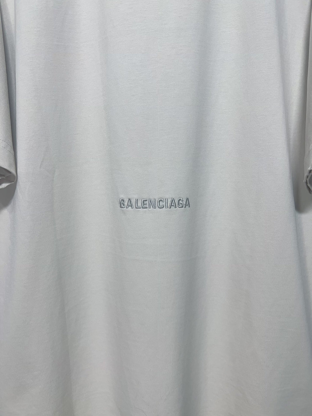 Close-up of white T-shirt with small Balenciaga logo near the hem