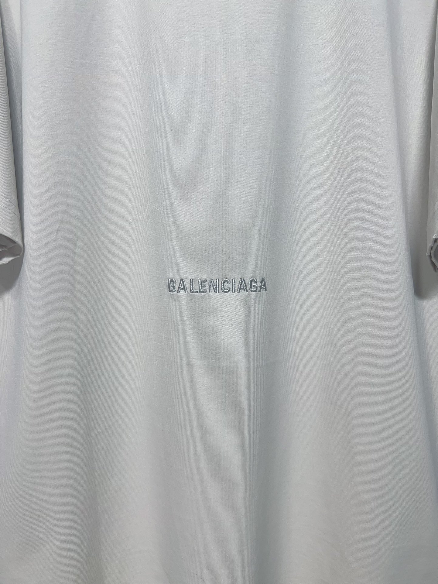 Close-up of white T-shirt with small Balenciaga logo near the hem