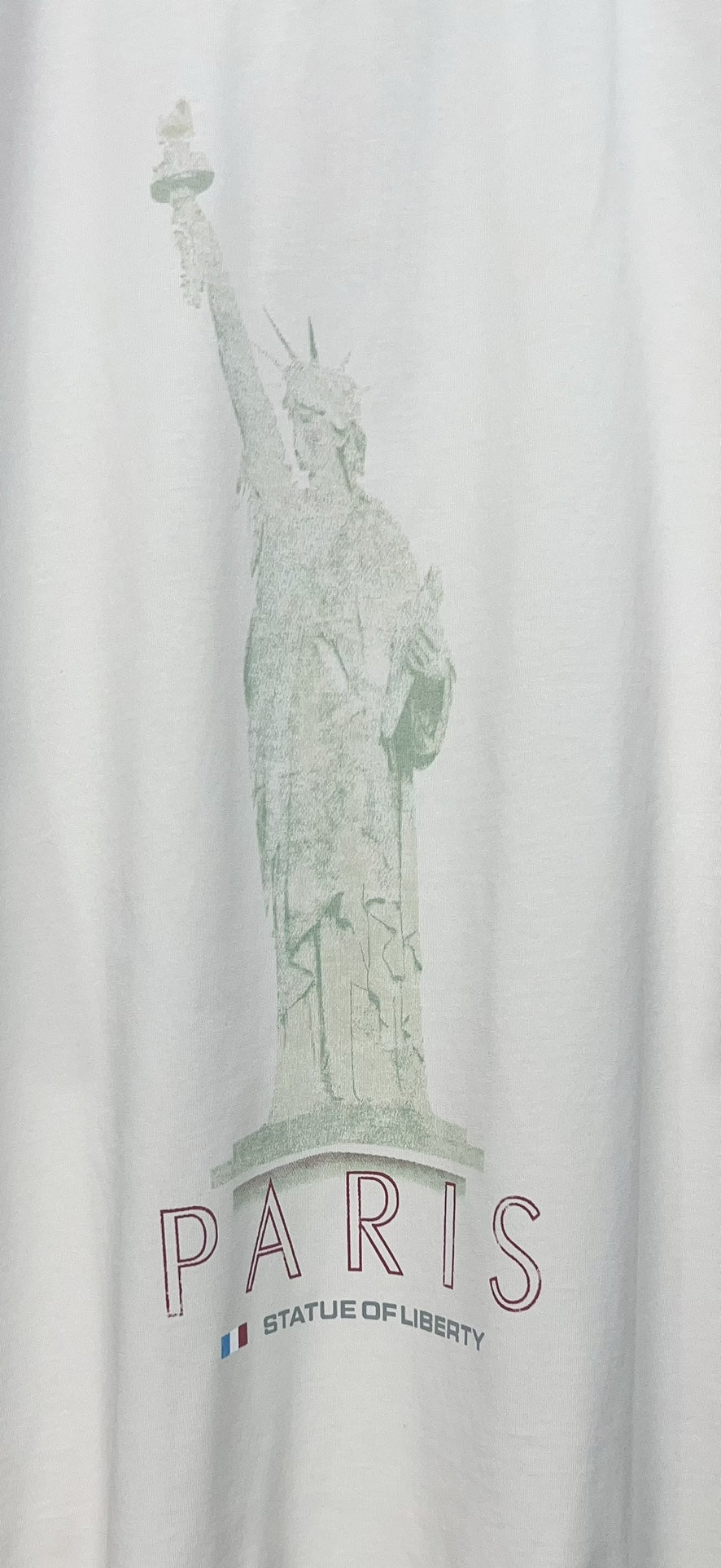 Close-up of white T-shirt featuring green Statue of Liberty and PARIS lettering