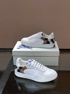 Burberry white sneakers with black-and-tan plaid side panel and blue logo detail
