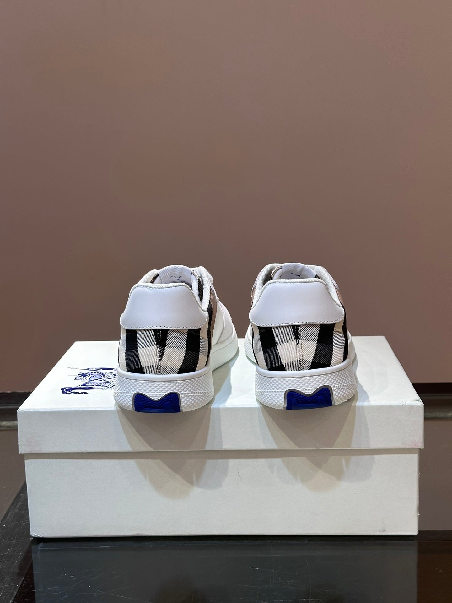 Burberry white sneakers with black-and-white plaid heel panels and blue logo accent