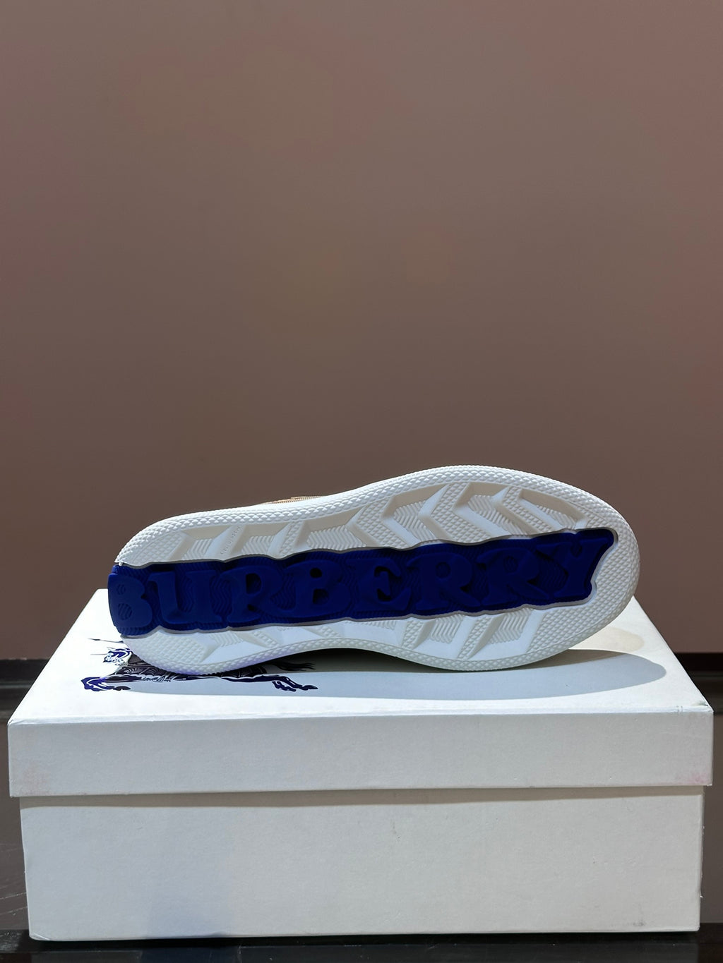 Outsole view of checkered low-top sneakers with blue logo on tread