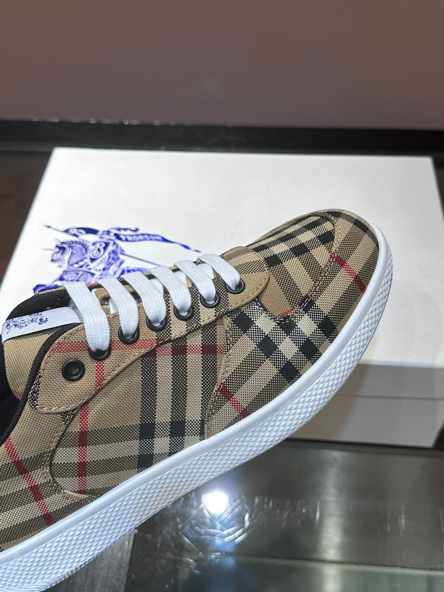 Close-up of checkered sneaker upper with white laces and blue horse logo patch