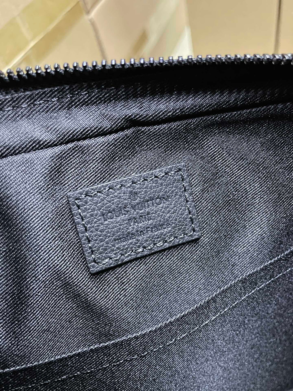 Louis Vuitton fabric pocket with stitched leather patch, dark black tone