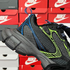 Unisex running shoe with black mesh upper, neon green and blue panels, chunky gray sole.