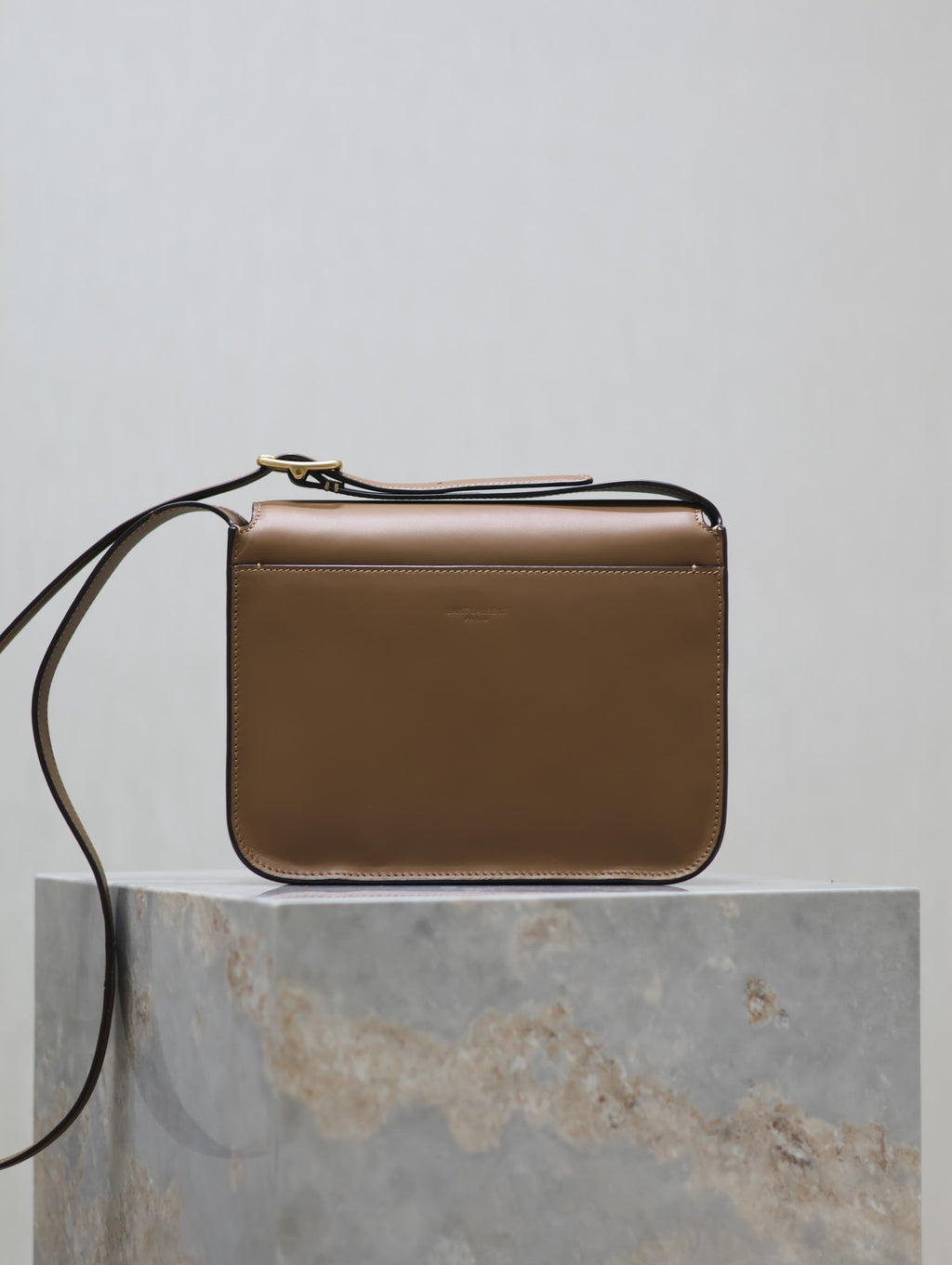 Tan structured crossbody bag with gold-tone top hardware and flat front