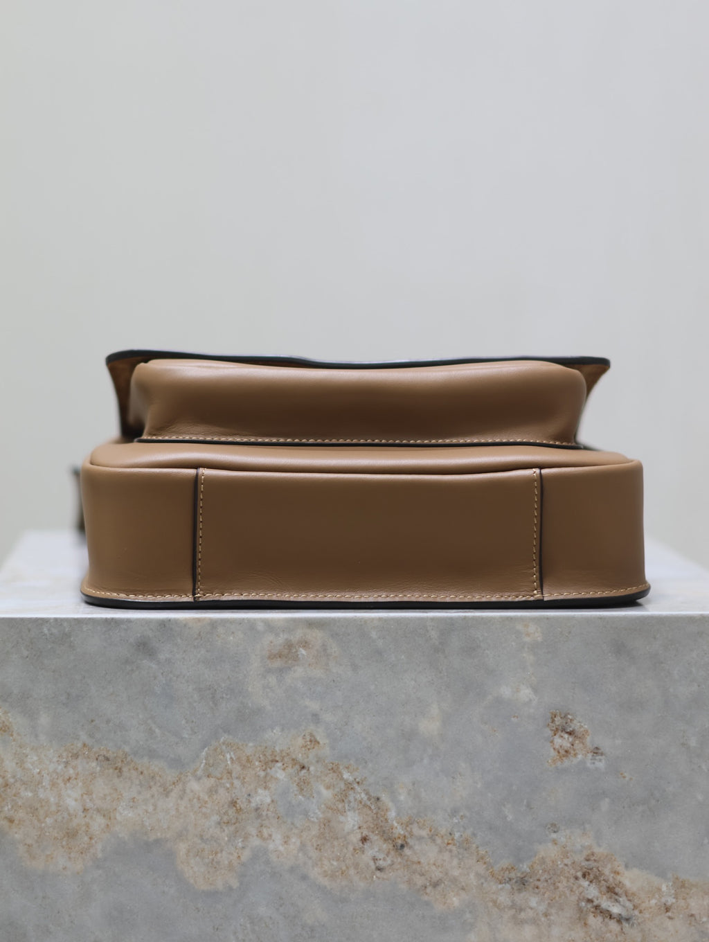 Tan leather mini bag with cushioned front panel and gold top hardware