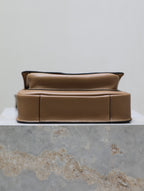Tan leather mini bag with cushioned front panel and gold top hardware