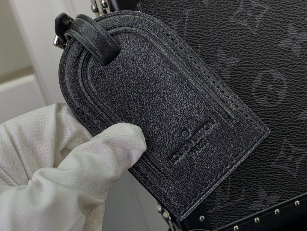 Men's Louis Vuitton bag close-up of embossed leather label and black textured exterior