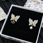 Gold-tone butterfly earrings with faux pearls on black display card