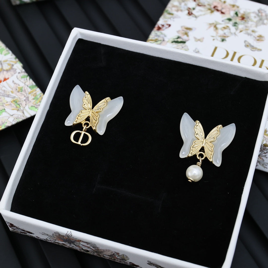 Gold-tone butterfly earrings with faux pearls on black display card