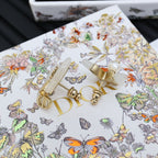 Gold-tone butterfly ear accessories with faux pearls and Dior logo detailing