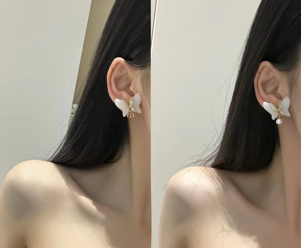 Butterfly earrings with faux pearls worn on model's ears, gold-tone