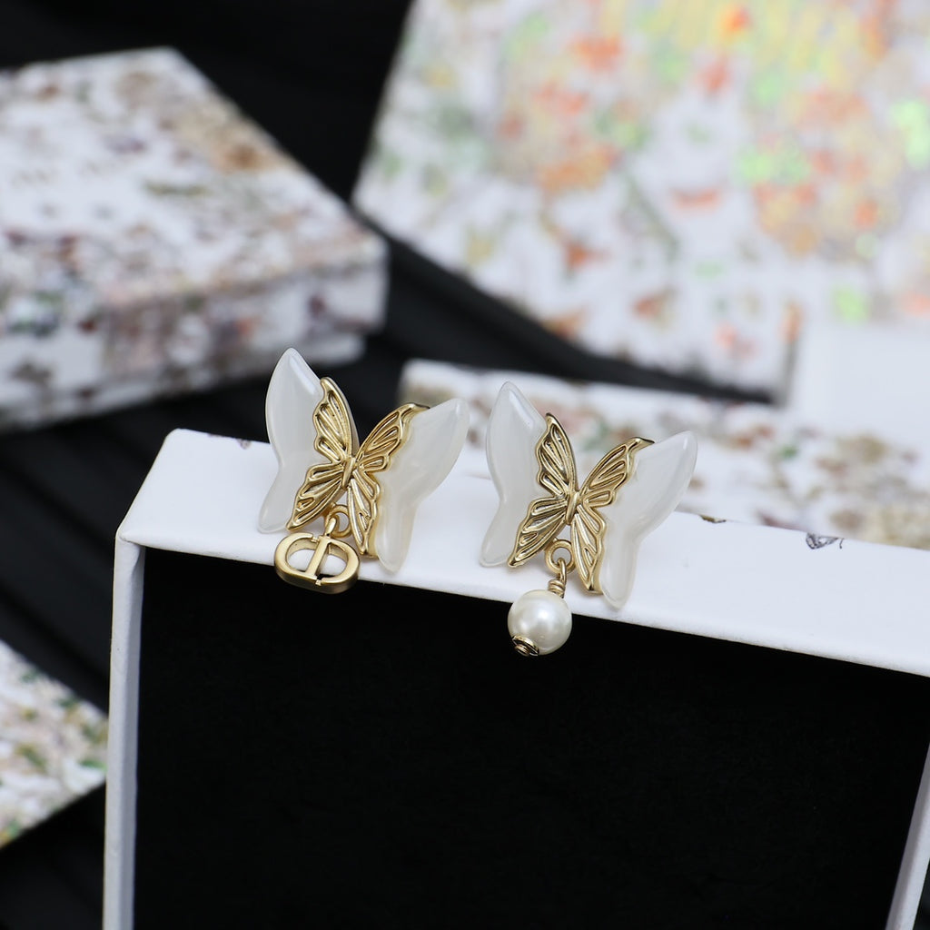 Gold-tone butterfly earrings with faux pearls on open white gift box