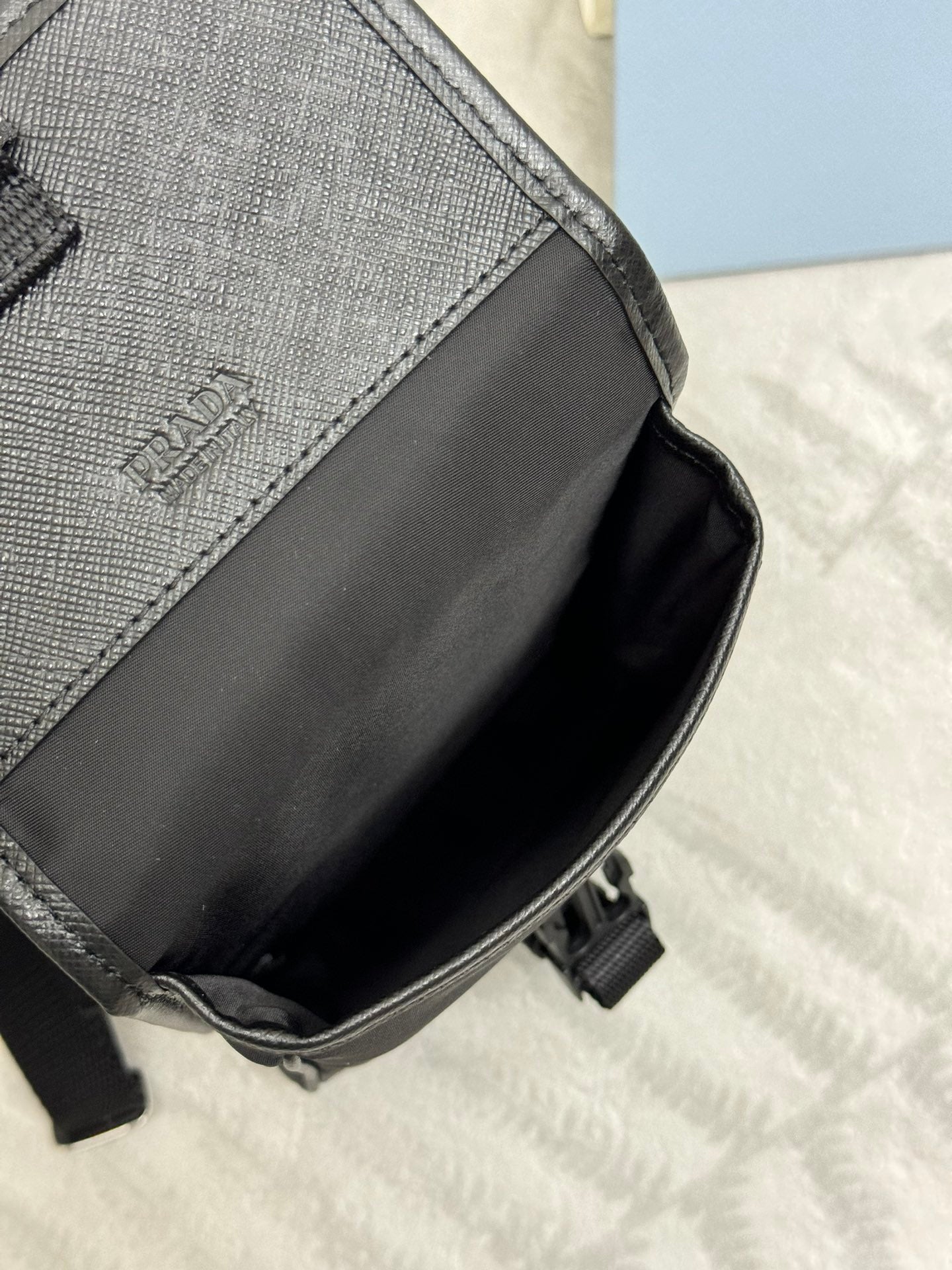 Prada black mini bag side panel with stitched trim and strap attachment