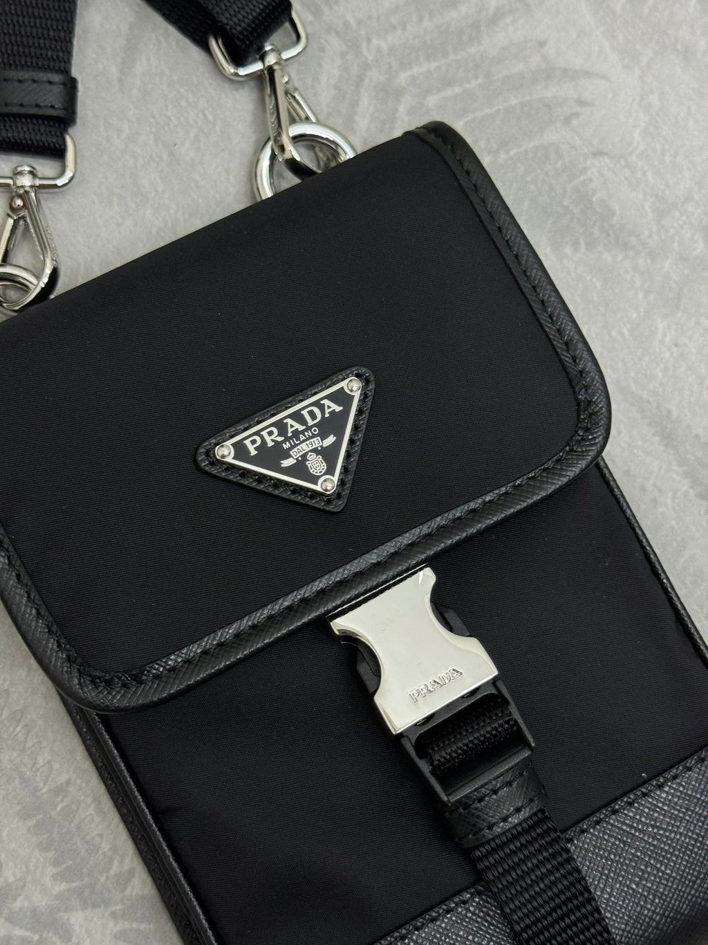 Prada black mini bag close-up of front logo plaque and strap buckle