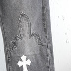 Chrome pants close-up of denim leg with stitched cross applique and contrast panel
