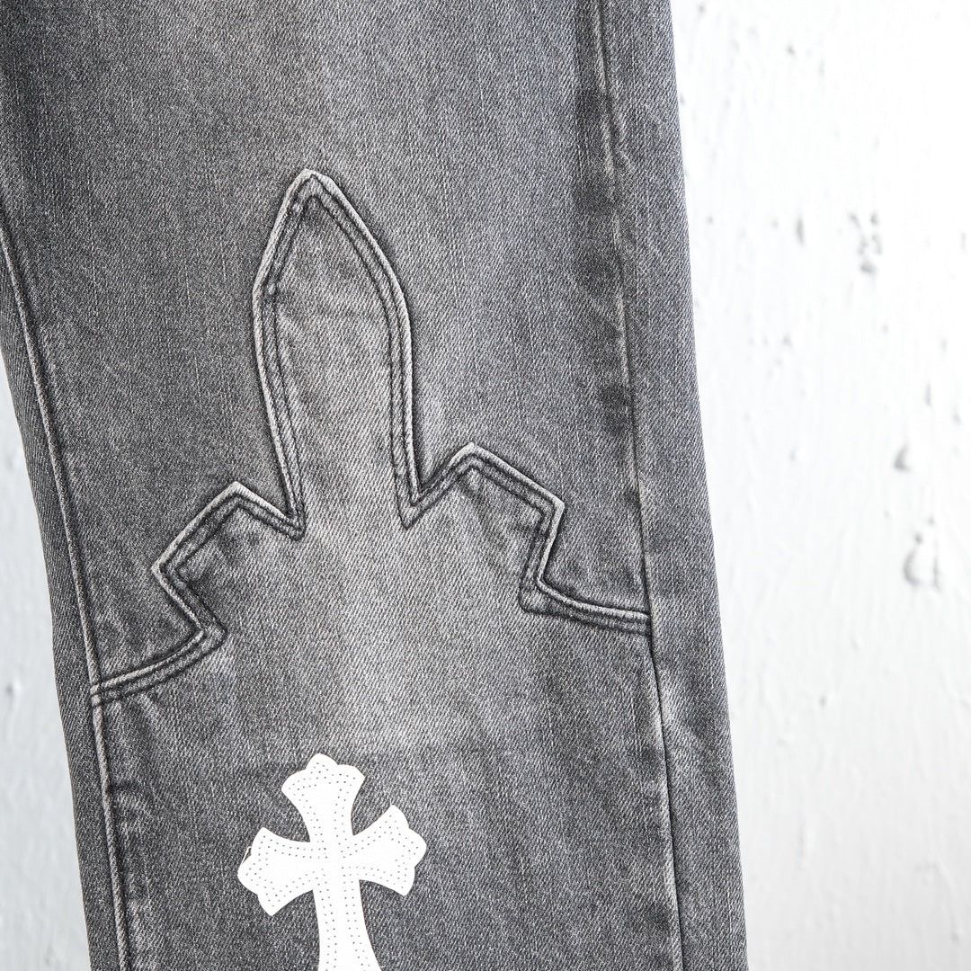 Chrome pants close-up of denim leg with stitched cross applique and contrast panel