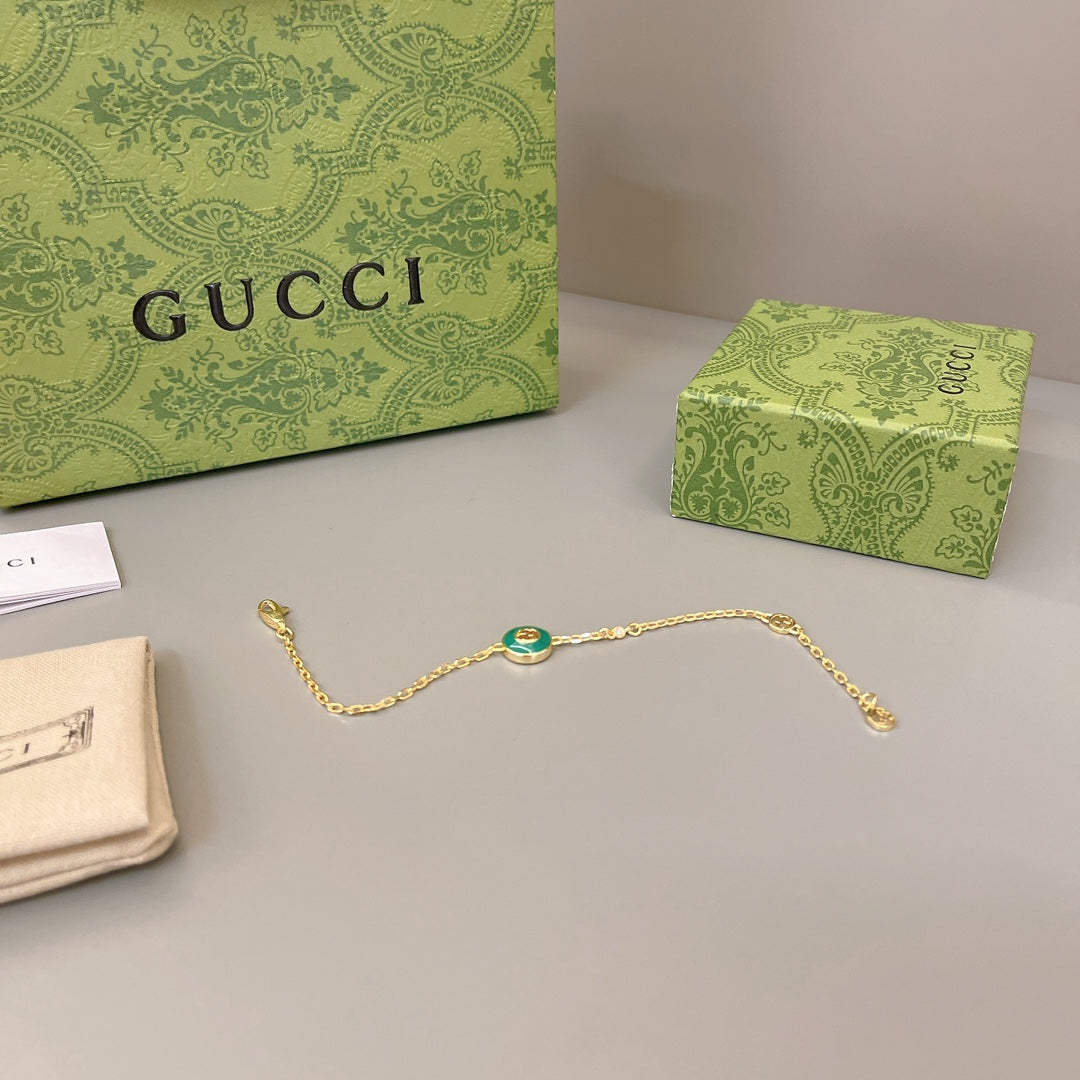 Gold chain bracelet with oval green enamel center charm