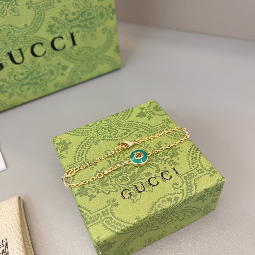 Gold chain bracelet with green enamel round charm and layered link style