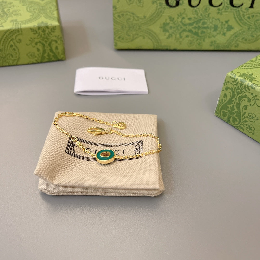 Gold charm bracelet with green enamel medallion and interlocking link