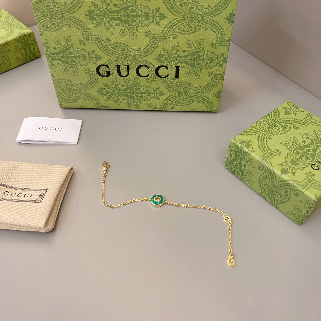 Gold chain bracelet with small green enamel round center charm