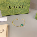 Gold chain bracelet with round green enamel charm and small dangling detail