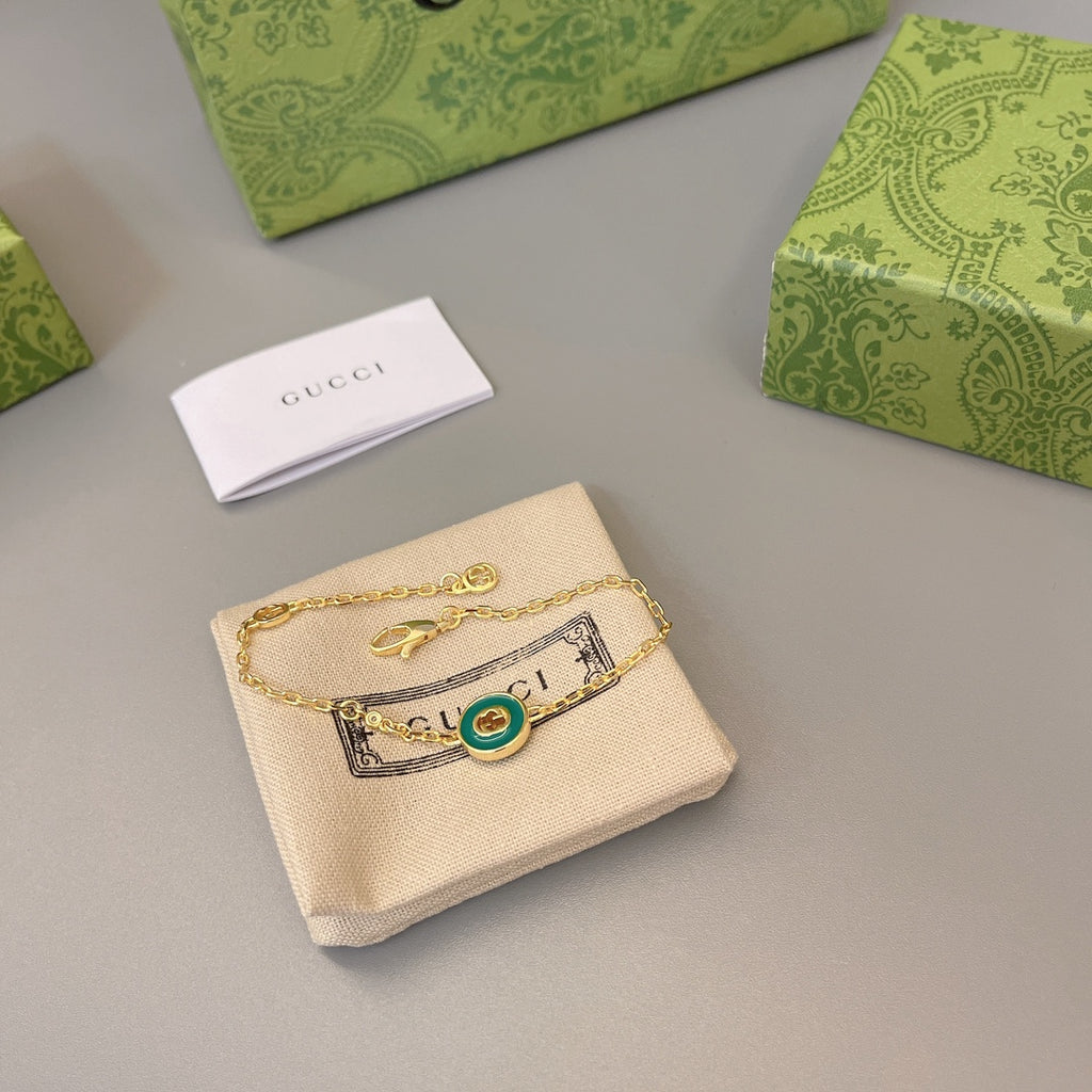 Gold charm bracelet with green enamel round charm and bar detail