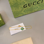 Gold bracelet with green enamel round charm and white tag with Gucci print