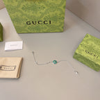 Gucci silver bracelet with green enamel charm, laid out with boxes