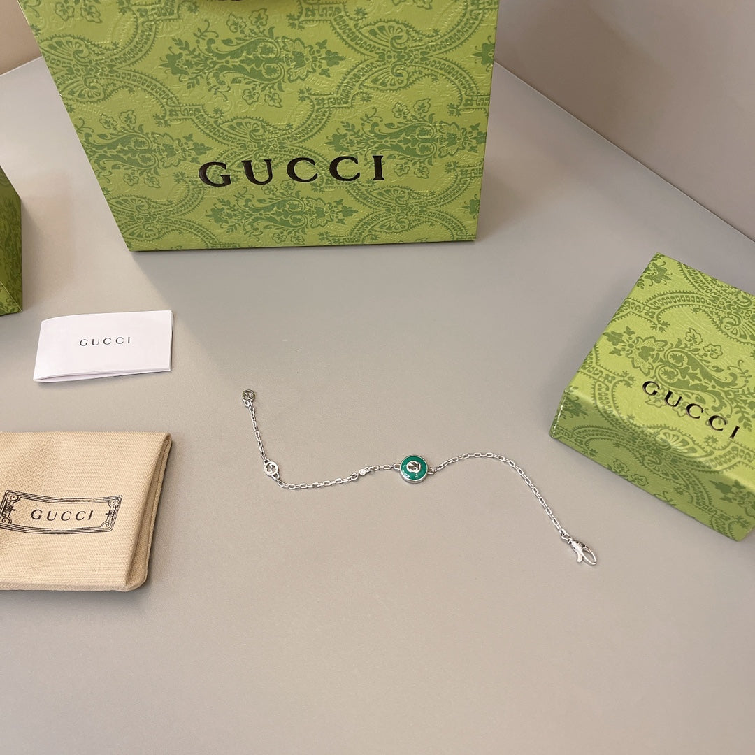 Gucci silver bracelet with green enamel charm, laid out with boxes