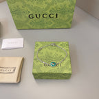 Gucci silver bracelet with green enamel charm on patterned gift box