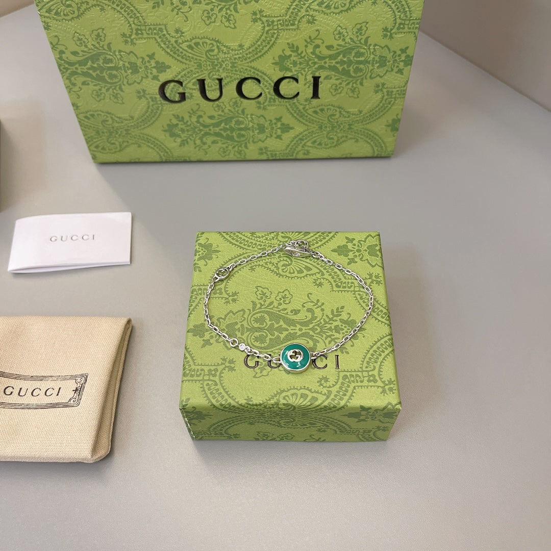Gucci silver bracelet with green enamel charm on patterned gift box