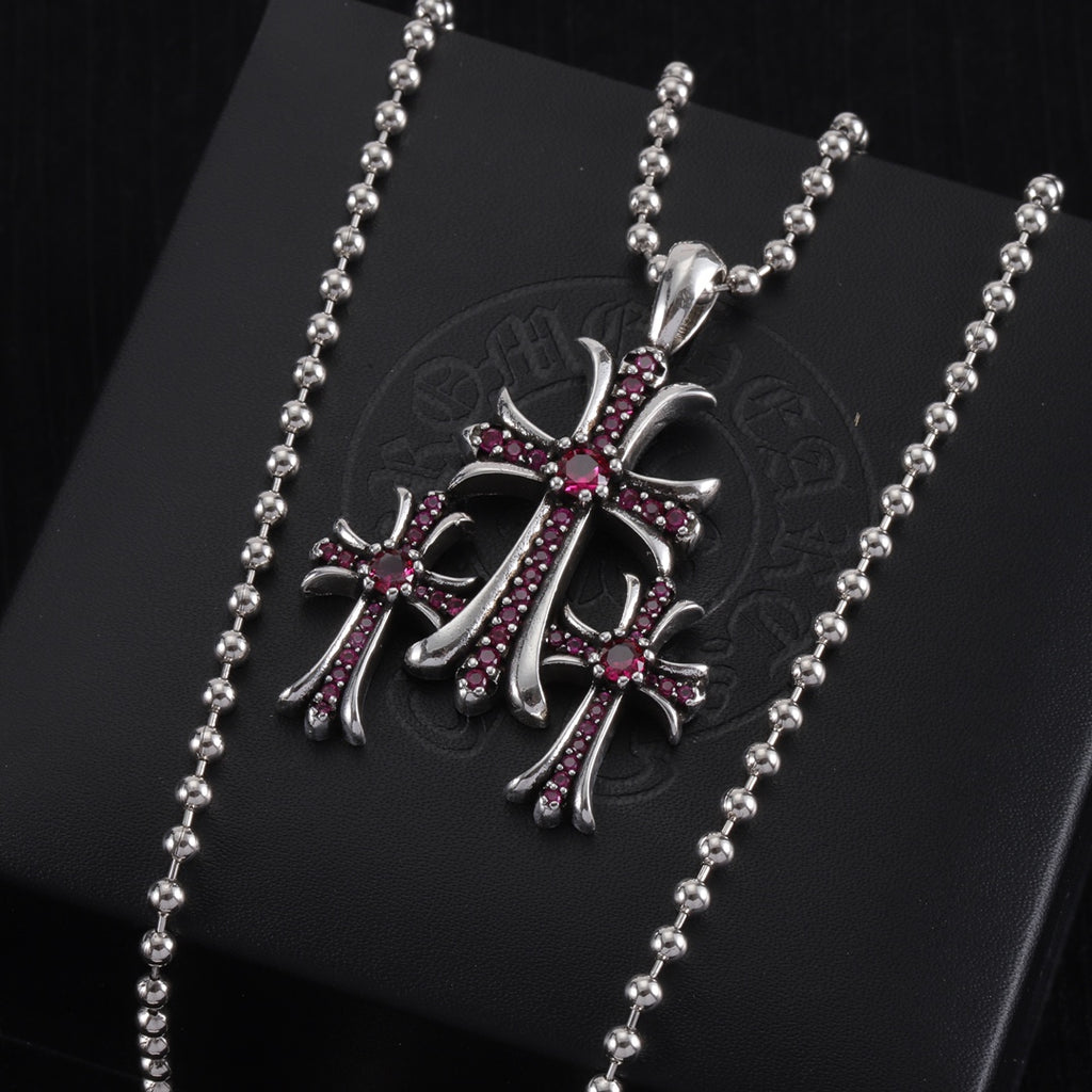 Pendant necklace with chrome cross charm and red/purple enamel, on card