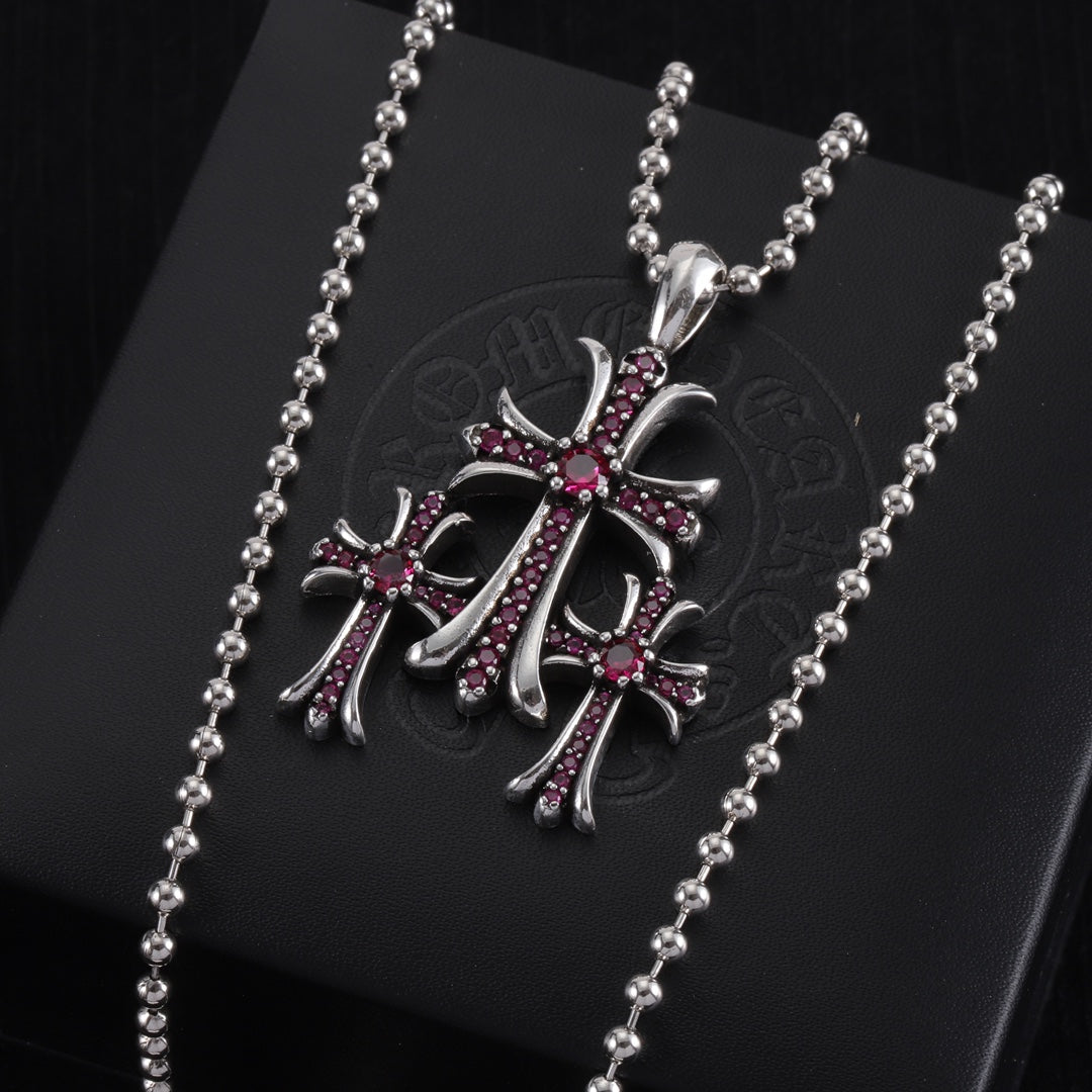 Pendant necklace with chrome cross charm and red/purple enamel, on card
