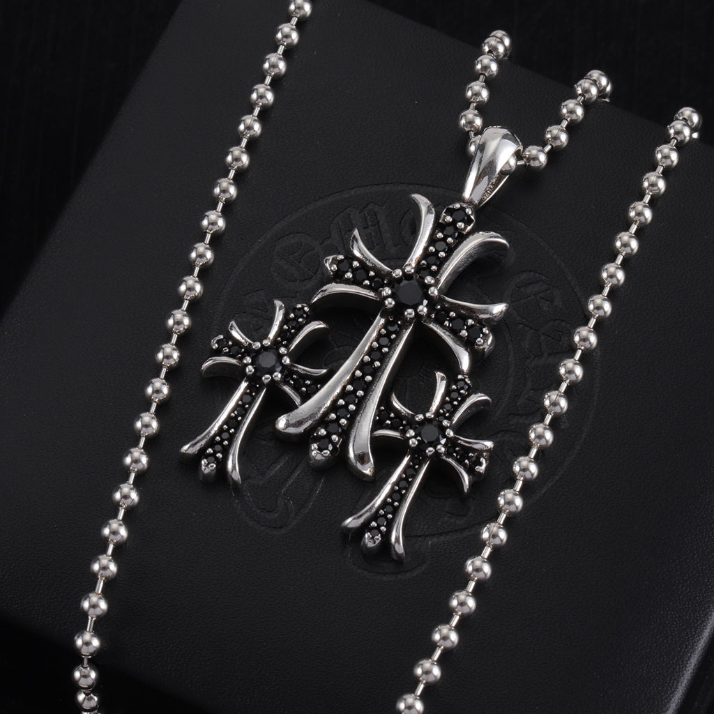 Pendant necklace with large chrome cross charm, dark enamel and small stones