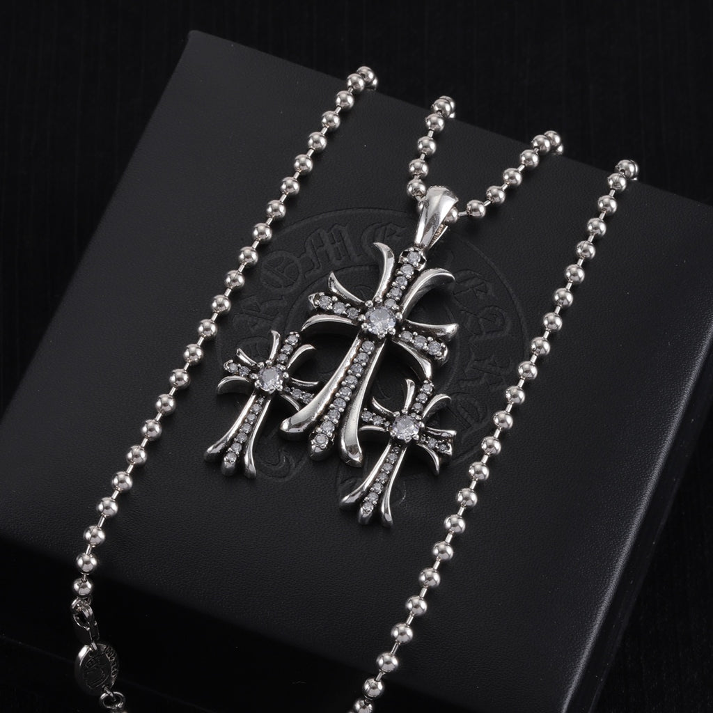 Pendant necklace with chrome cross charm, clear stones and dark enamel, on card