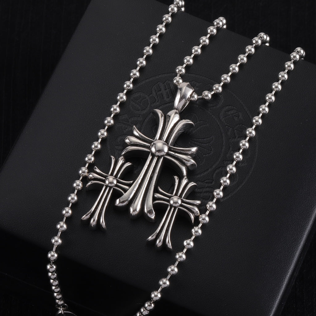 Pendant necklace with chrome cross charm and small round stones, on card