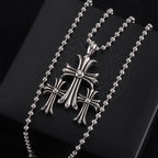 Pendant necklace with chrome cross charm and small round stones, on card