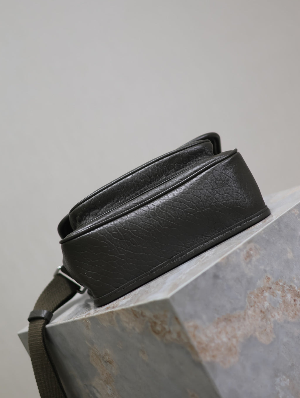 YSL crossbody bag rear view in black textured leather, strap across the back